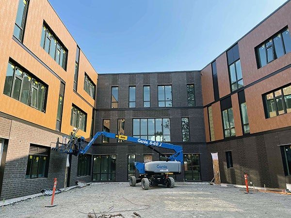 a Genie-lift in an unpaved couryard surrouded by a 3-story building