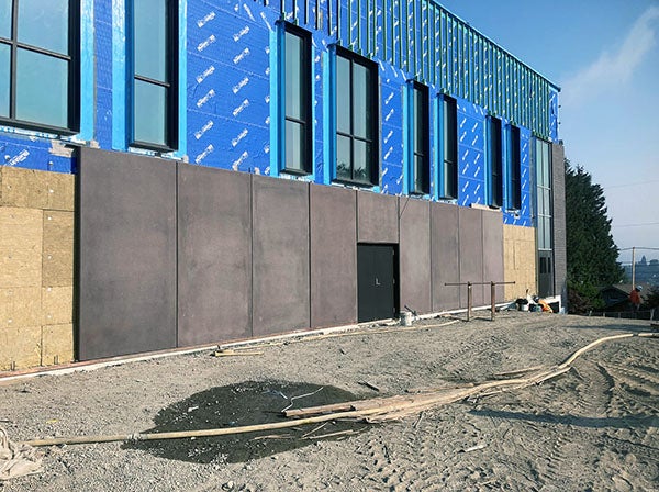 a large building exterior with unfinished walls above concrete panels