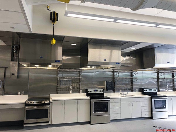 a large room with three stoves with counters between them and metal wall racks behind them