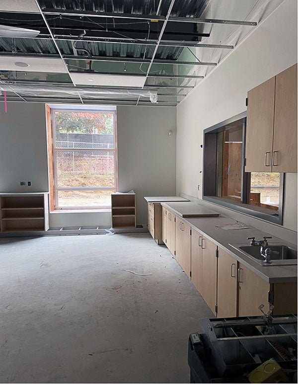 an unfinished room has cabinets and a ceiling grid