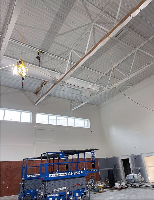 a ceiling with exposed trusses with wood on one side of one truss