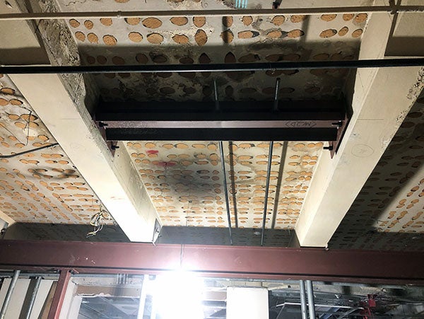 a ceiling with no tiles and a steel i-beam perpendicular to two existing beams