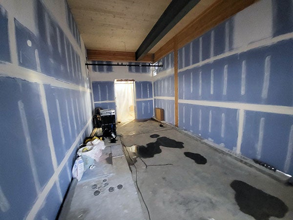a narrow room with wallboard and wallboard tape and mud on walls