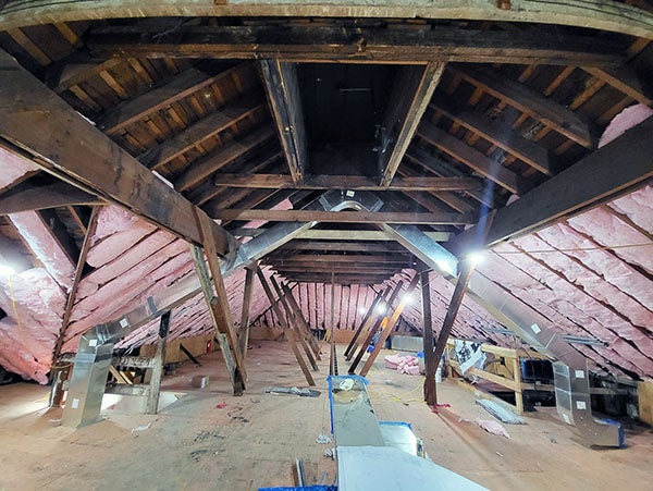 inside of a building with the wood framing showing and pink insulation in parts of it