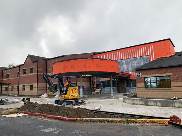 a brick building has a round entry canopy attached to an area under construction