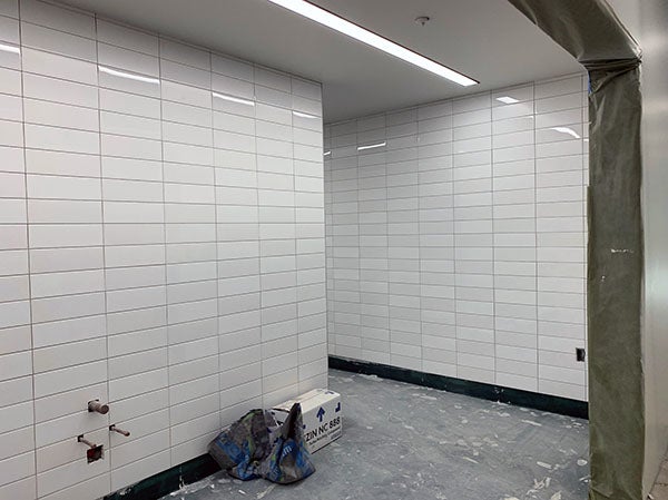 white rectagular tiles cover two walls with a space between them