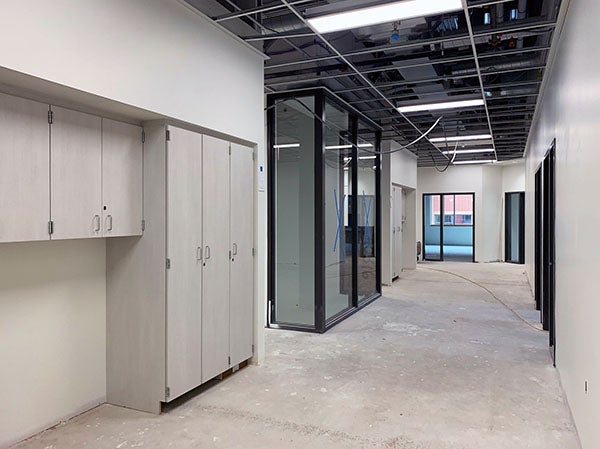 hallway with a glassed in room and some cabinets - none are finished