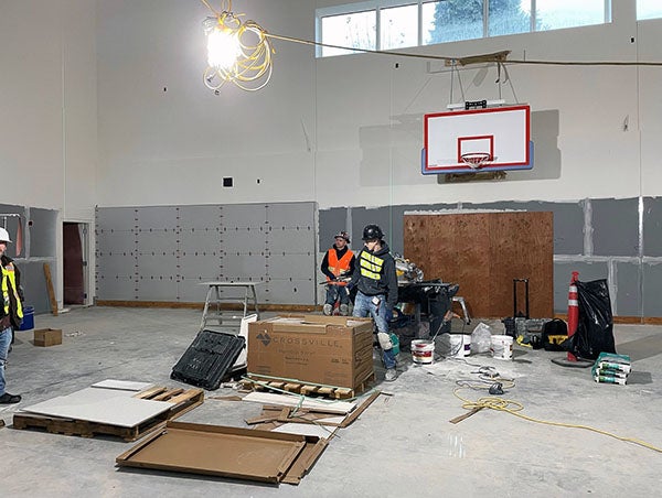workers with a large box in front of a wall with a basketball hoop above