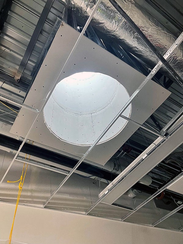 a round skyslight in a ceiling grid with no ceiling tiles