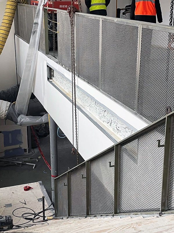 a wall beside a stairway with an indent so you can see a structural steel beam with writing on it