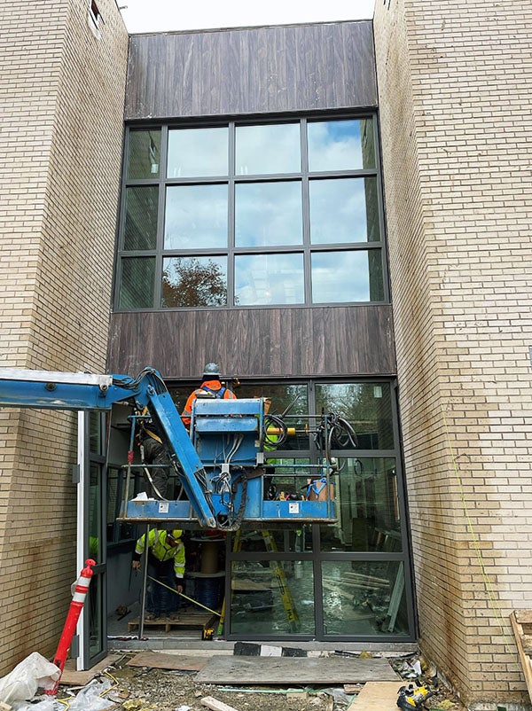 a lift truck with a worker in front of the exterior of a building with two brick walls next to them