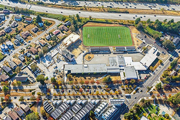 aerial photo of a long building a playfield, an old building and a construction project