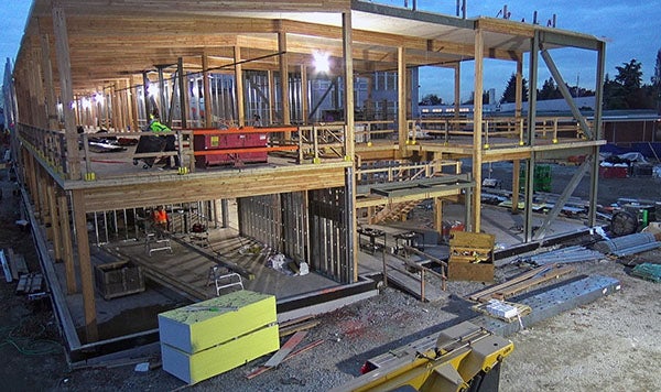 a two story building under construction with no exterior walls, wood beams, and interior metal studs