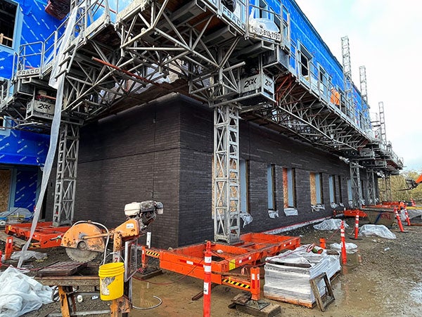 scaffoding above the first floor of a dark brick building under construction