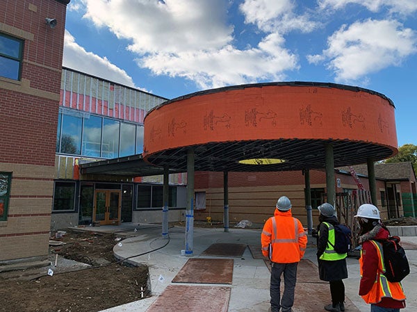 a curved canopy with a walk way to a building entrance