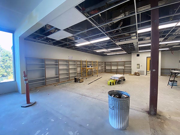 a large room with no ceiling tiles or flooring and with some shelving on two walls