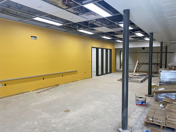a large yellow wall in a large room with no floor coverings or ceiling tiles