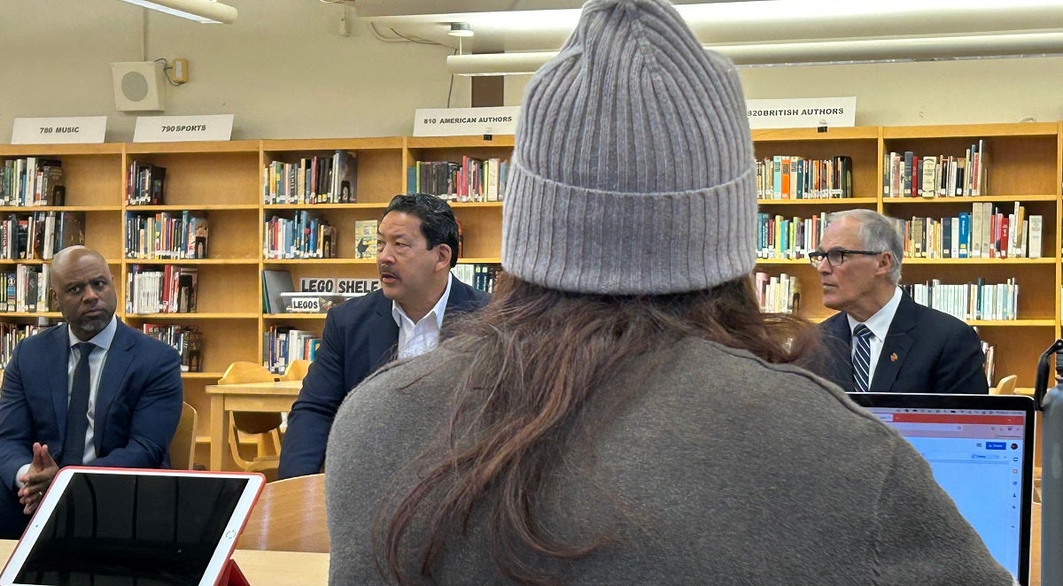 Superintendent Jones, Mayor Harrell, and Governor Inslee talk with students in the school library.
