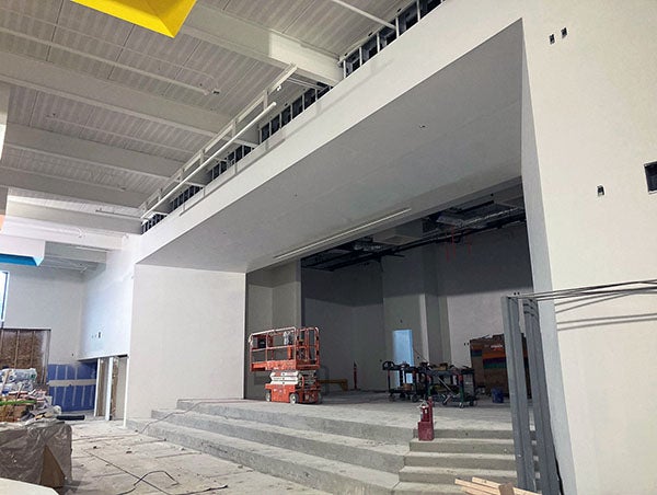 a stage area with unfinished concrete stairs is in a large room with floors covered for protection