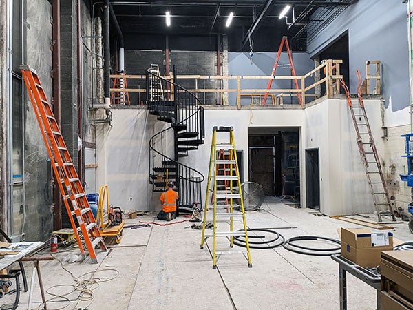 a black metal spiral staircase goes from the floor level to raised area under construction