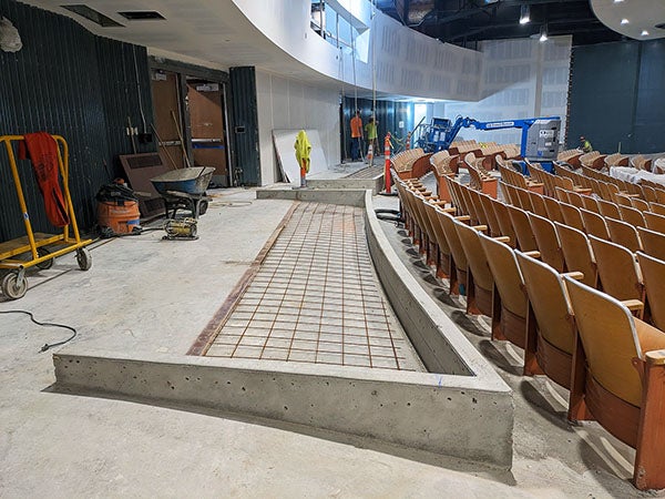 a concrete floor behind theater seats has a short wall on three sides with a grid inside