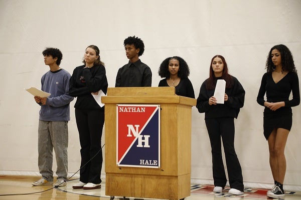 A group of students talk to a school assembly