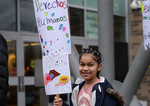 A student smiles while holding a sign at a school march
