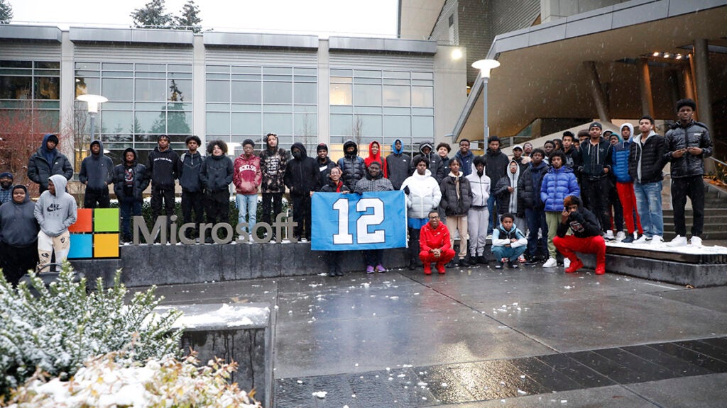 A large group of students gather for a photo in front of the Microsoft campus sign