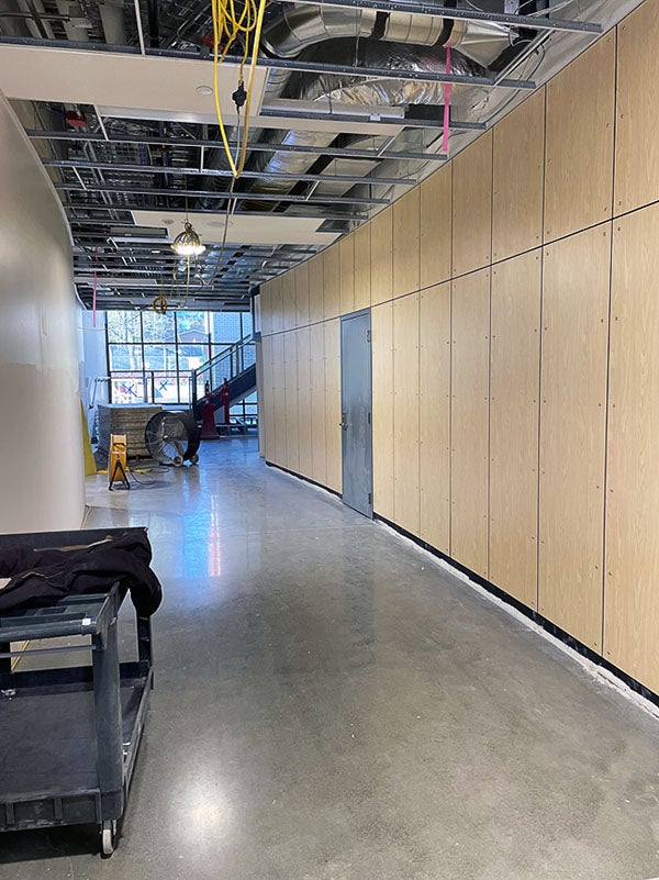 an interior hallway with a polished concrete floor and wood paneling. the ceiling grid is still open except for a few tiles
