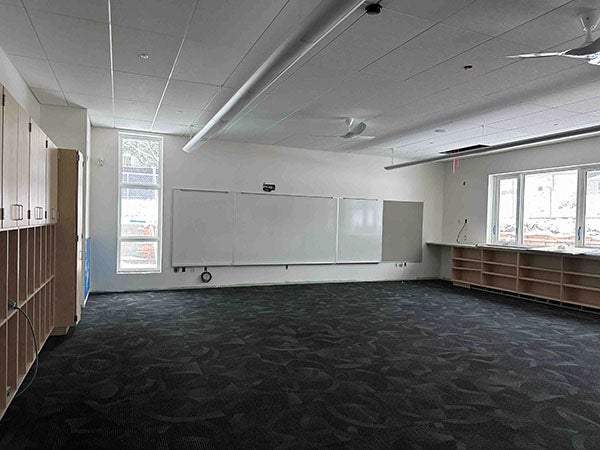 a classroom with cabinets, carpet, and a white board -- no furniture