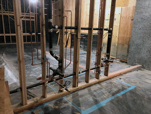 wood framing between concrete walls has pipes attached