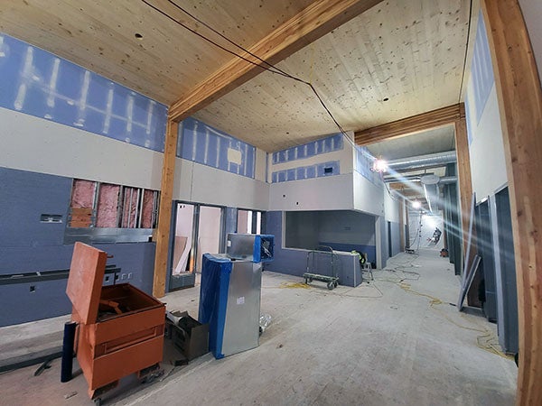 drywall being installed in a room with wood beams and a wood ceiling
