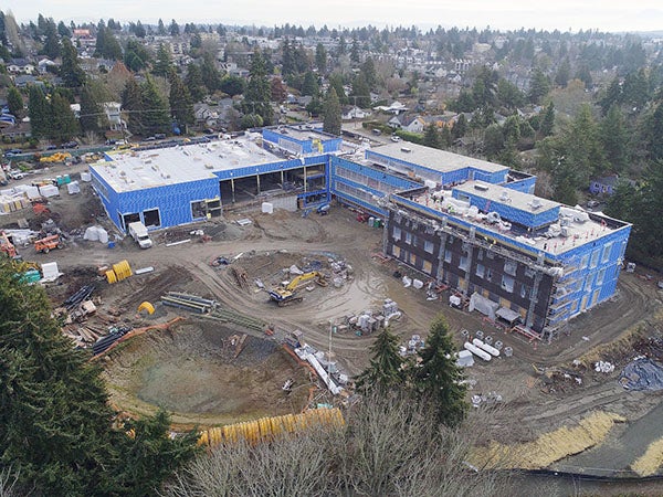 aerial view of a very large multi story building with a large tree preserved in the construction site