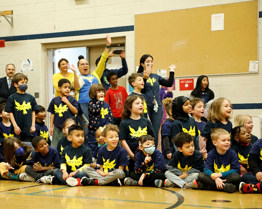 Students and teachers react to a surprise assembly in the school gym