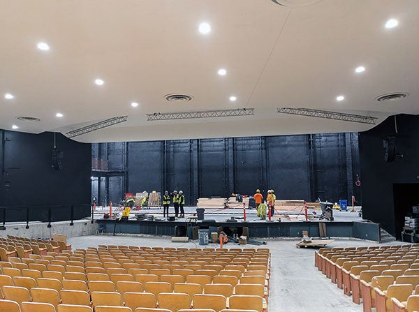 an auditorium with theatre seats with construction workers on the stage