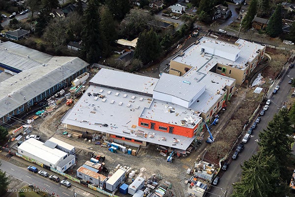 aerial photo of a large building under construction with an older large building to the left
