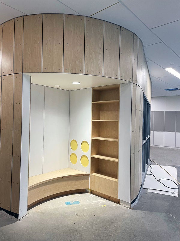 a rounded wall has a small space with a bench and shelves. the floor is concrete