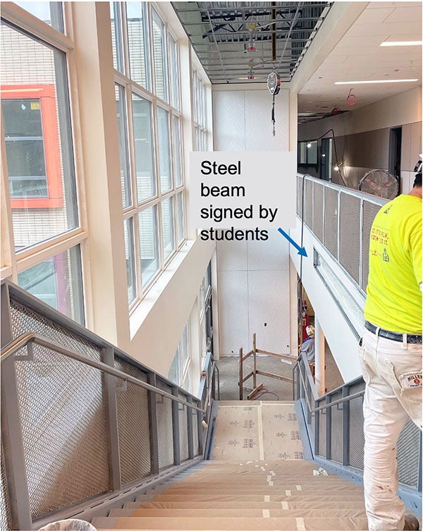 looking down a stairway with windows on one side. cardboard is on the steps. a railing is between the top of the stairs and a walkway.