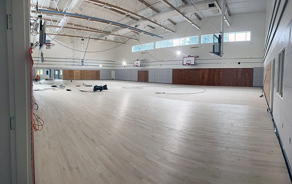 a large room with basketball hoops with a wooden floor installed halfway across