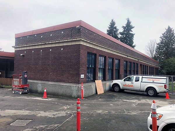 the corner of a brick building with a flat roof. a truck sits in front