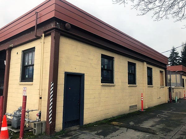 a yellow painted brick building with a rust colored cornice has windows