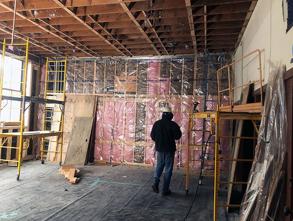 a wood framed wall and ceiling has pink insulation behind clear plastic