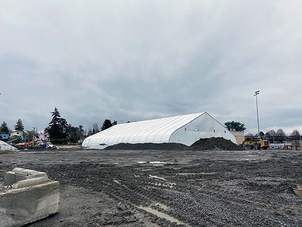 a large white tent sits in a muddy construction site