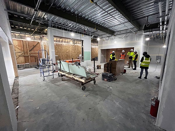 interior of a large room under construction with workers and equipment, a metal ceilding, and partially finished walls