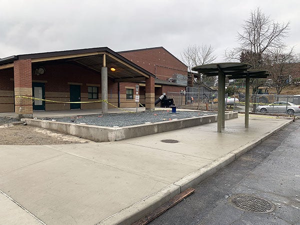 a brick building with a one story covered outdoor area and an uncovered area with a concrete curb