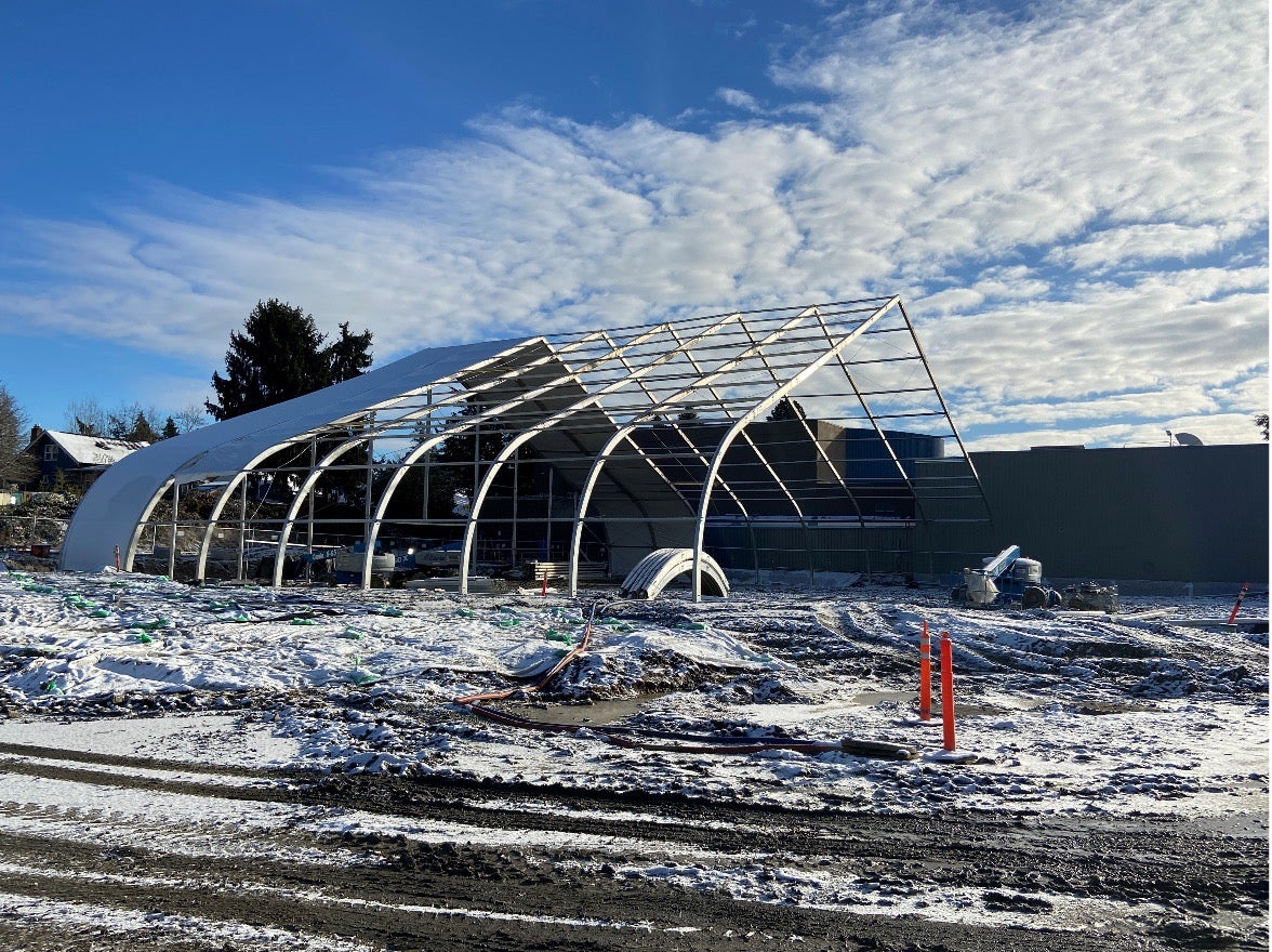 a metal frame in the shape of a tent is in a snow covered dirt construction site