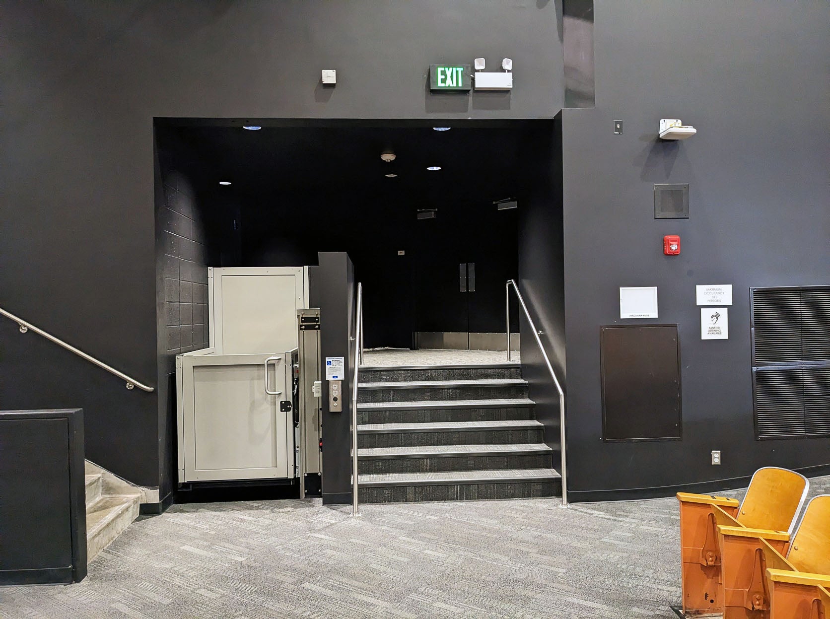 a mobility lift is shown next to a short set of six stairs with black walls around both