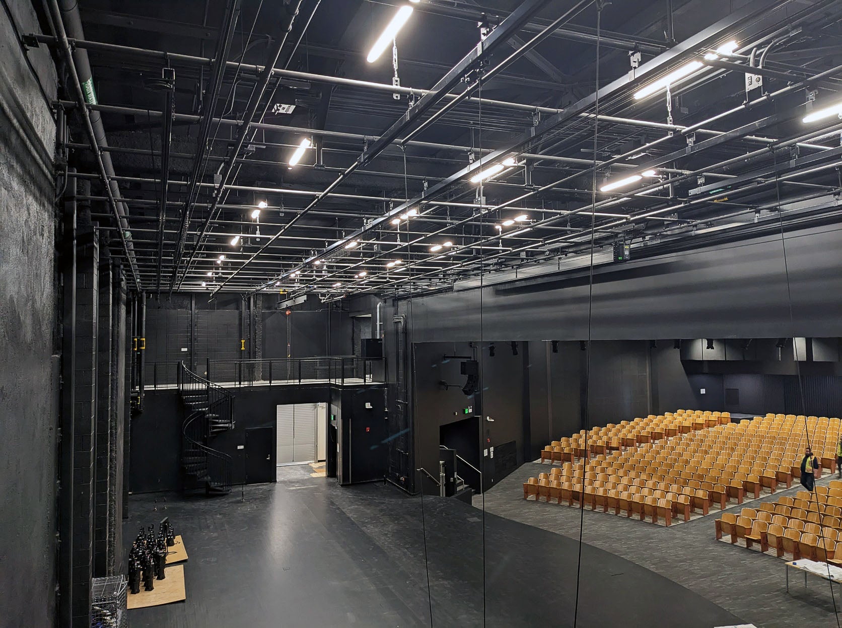 a grid of rigging hardware is shown above a stage with a view of the auditorium audience area
