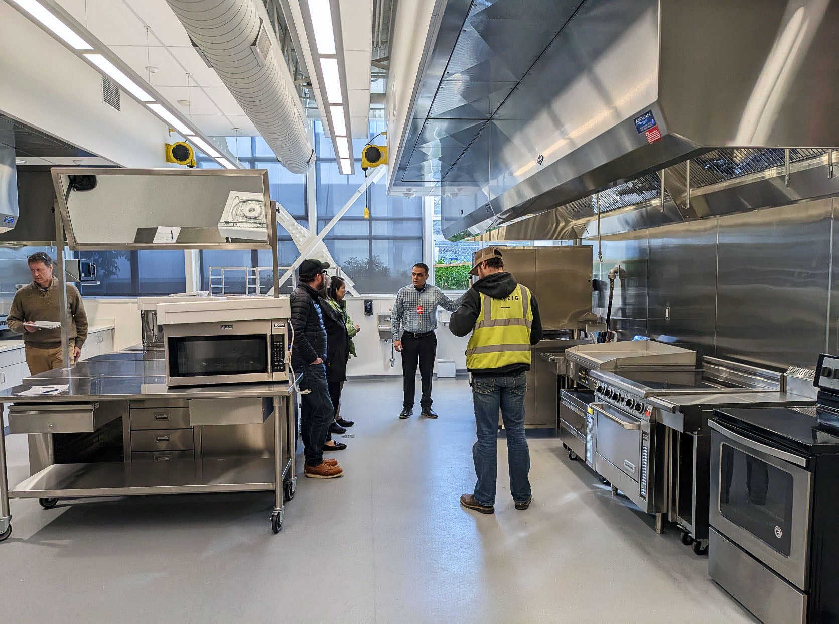 a group of people look at commercial size stainless steel cooking equpiment