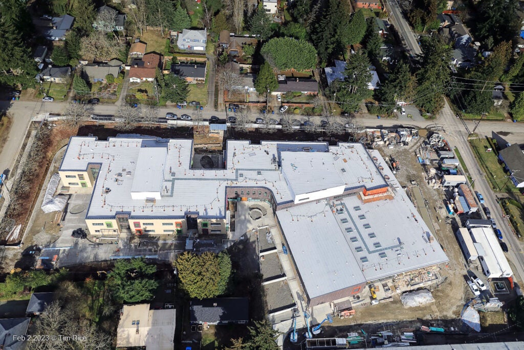 aerial of a large building with two wings surrounded by a street and houses